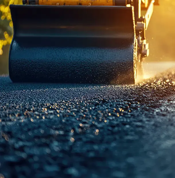 Roller drum compacting loose stone on a job site