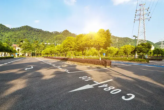 Marked asphalt roadway running past a hillside