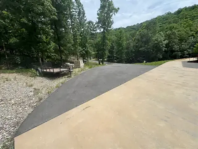 Newly paved driveway curving through a wooded property