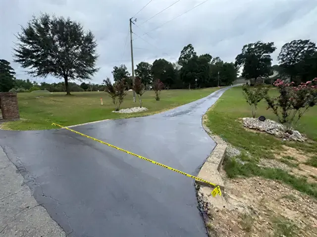 New asphalt driveway with caution tape crossing a lawn