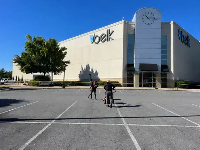 Crew pulling a hose across an empty shopping-centre parking lot