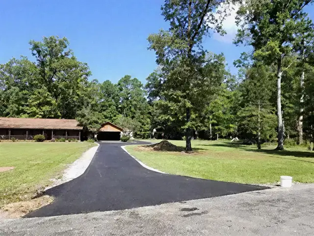 Fresh asphalt drive leading to a long ranch-style building