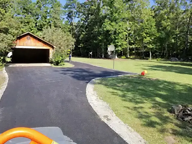 Newly paved driveway curving toward a garage