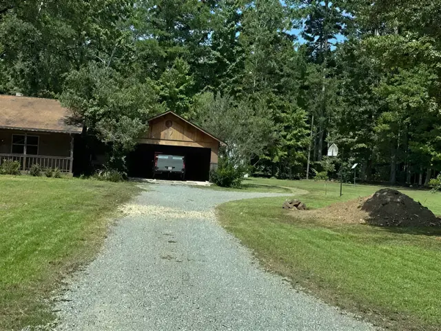 Gravel and asphalt drive up to a cabin in the woods